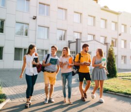Five friendly students are walking after they passed test outside the college building and discuss the project